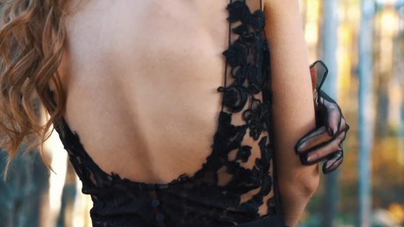 A close-up of a bride in a black lace wedding gown with an open back, showing elegant floral detailing and sheer fabric